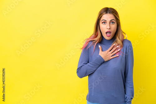 Young woman over isolated yellow background surprised and shocked while looking right © luismolinero