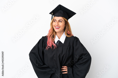 Young university graduate over isolated white background posing with arms at hip and smiling