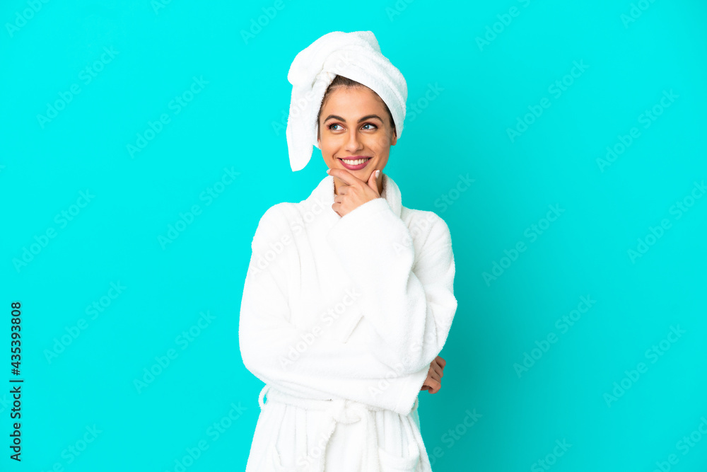Young woman in a bathrobe over isolated blue background looking to the side and smiling Young woman in a bathrobe over isolated blue background looking to the side and smiling