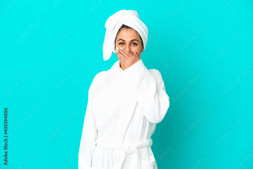Young woman in a bathrobe over isolated blue background happy and smiling covering mouth with hand Young woman in a bathrobe over isolated blue background happy and smiling covering mouth with hand
