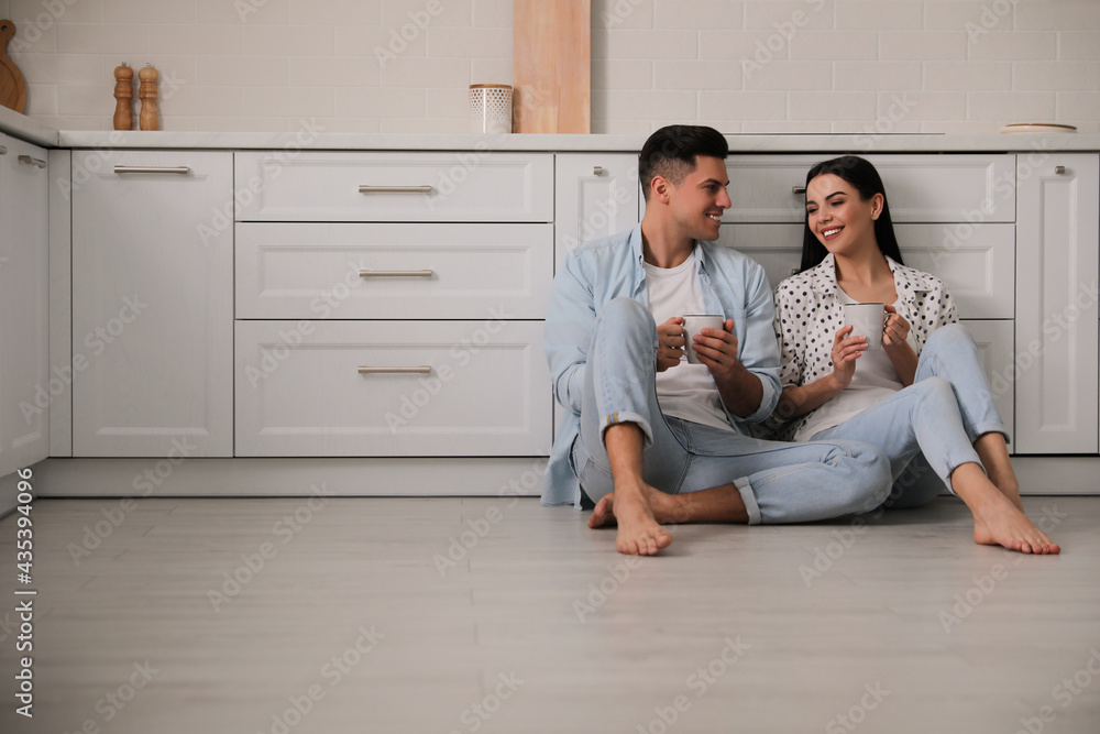 Happy couple sitting on warm floor in kitchen. Heating system Happy couple sitting on warm floor in kitchen. Heating system