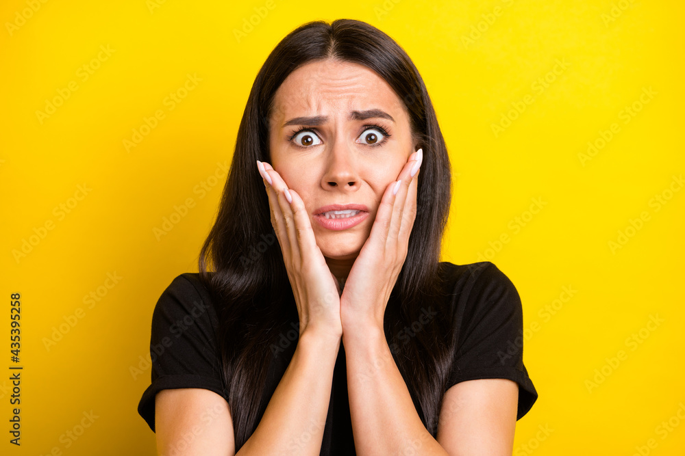Photo of scared worried lady palms cheeks look camera wear black t-shirt isolated yellow color background Photo of scared worried lady palms cheeks look camera wear black t-shirt isolated yellow color background