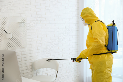 Employee in protective suit sanitizing office. Medical disinfection © New Africa