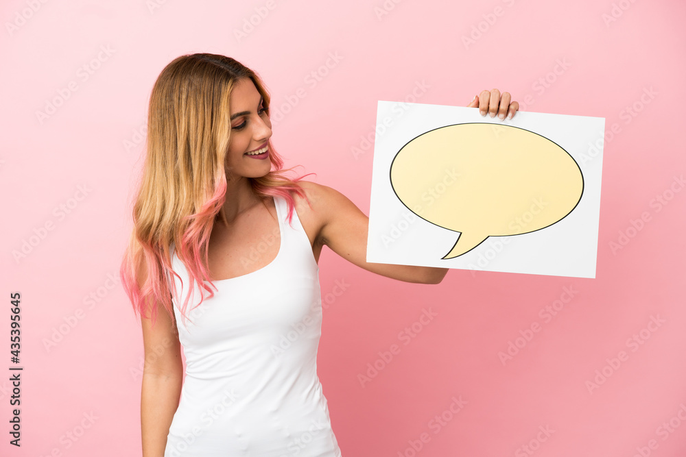 Young woman over isolated pink background holding a placard with speech bubble icon