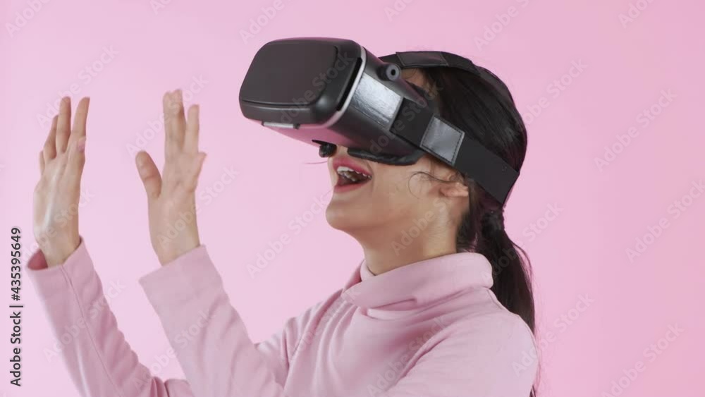 Beauty concept of 4k Resolution. Smile young woman wearing using virtual reality VR glasses helmet headset on pink background. Beauty concept of 4k Resolution. Smile young woman wearing using virtual reality VR glasses helmet headset on pink background.