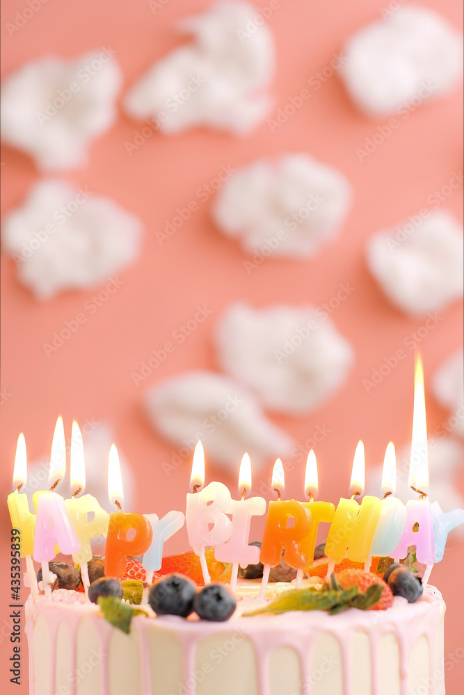 Happy Birthday cake. Beautiful cake with candle title Happy Birthday on pink background with white clouds. Close-up and vertical view Happy Birthday cake. Beautiful cake with candle title Happy Birthday on pink background with white clouds. Close-up and vertical view