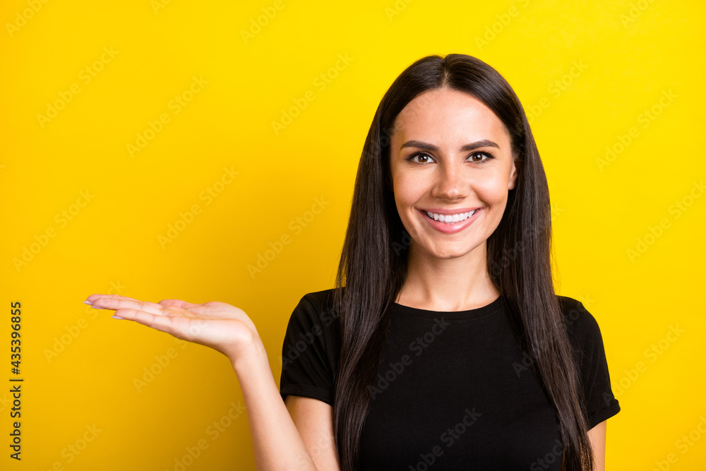 Photo of pretty cheerful brunette lady arm palms show holding empty space isolated on yellow color background Photo of pretty cheerful brunette lady arm palms show holding empty space isolated on yellow color background