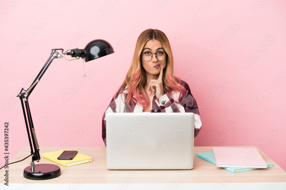Young student woman in a workplace with a laptop over pink background and thinking Young student woman in a workplace with a laptop over pink background and thinking