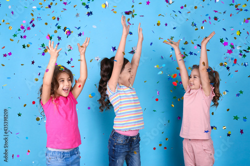Adorable little children and falling confetti on light blue background