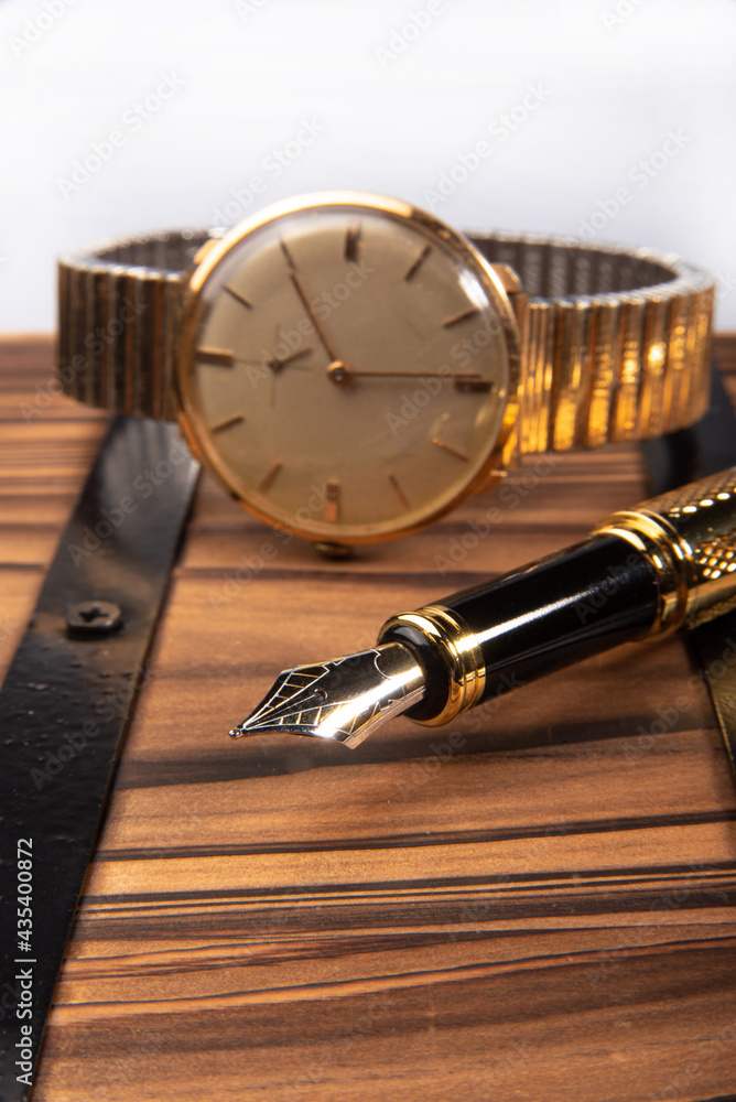 Fountain pen, beautiful fountain pen in detail on rustic wood along with an old clock, selective focus.