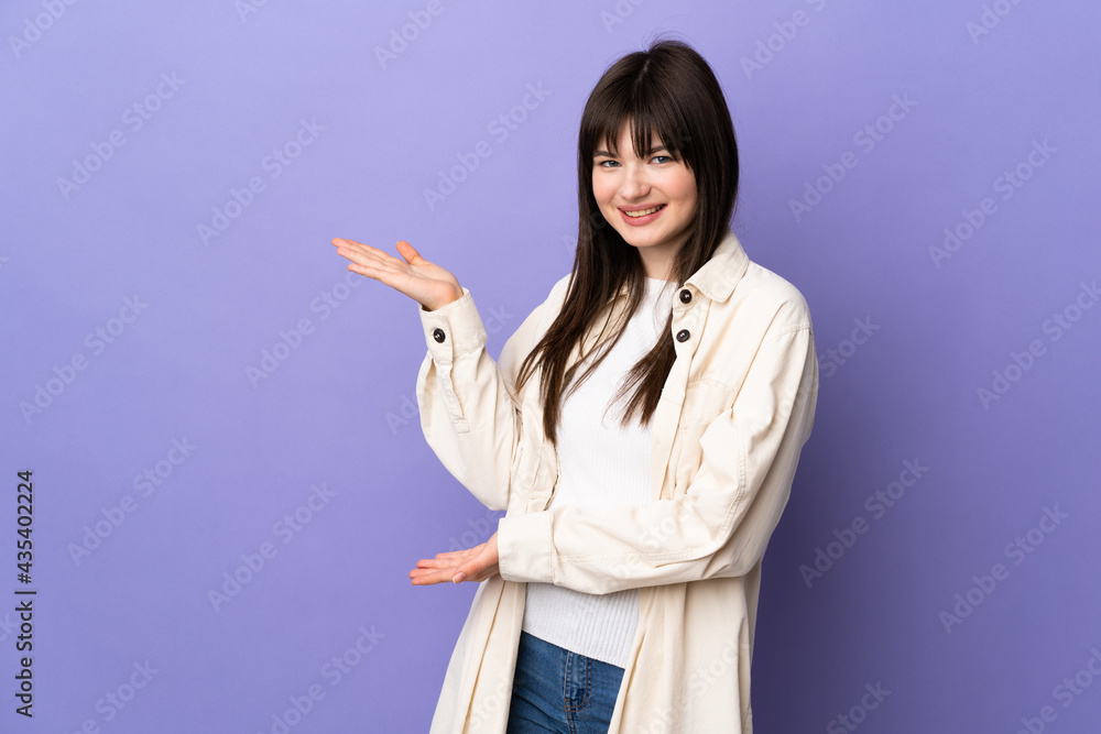 Young Ukrainian woman isolated on purple background extending hands to the side for inviting to come Young Ukrainian woman isolated on purple background extending hands to the side for inviting to come