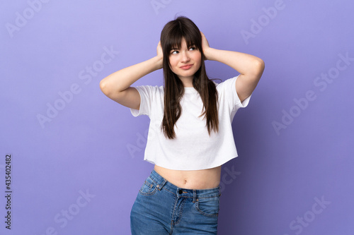Young Ukrainian woman isolated on purple background frustrated and covering ears