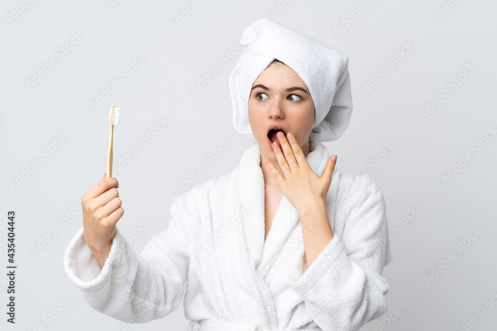 Young woman in a bathrobe holding toothbrush with surprise and shocked facial expression Young woman in a bathrobe holding toothbrush with surprise and shocked facial expression