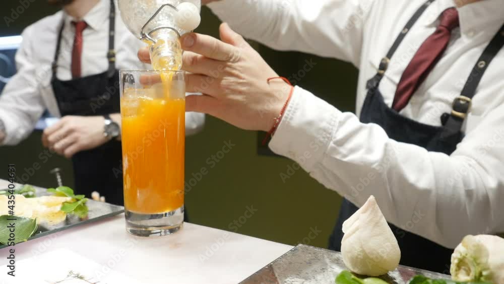 Bartender Combining Ingredients And Making Cocktail In A Trendy Bar. Bartender Pouring Cocktails In A Trendy Bar. Cocktails With Orange In Glasses. Bartender Combining Ingredients And Making Cocktail In A Trendy Bar. Bartender Pouring Cocktails In A Trendy Bar. Cocktails With Orange In Glasses.