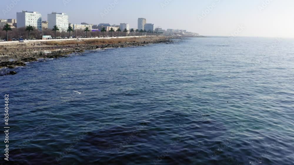 Aerial bird's eye view of ocean of island edge on coastline washed with splashing waves, drone shooting flight of seagull at nature environment at seashore with touristic people Aerial bird's eye view of ocean of island edge on coastline washed with splashing waves, drone shooting flight of seagull at nature environment at seashore with touristic people