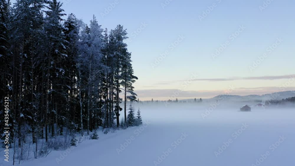 Drone shooting idyllic place with farmland in snowscape located in snowy environment with pine forest, picturesque Lapland landscape for visiting during getaway journey trip to North Drone shooting idyllic place with farmland in snowscape located in snowy environment with pine forest, picturesque Lapland landscape for visiting during getaway journey trip to North