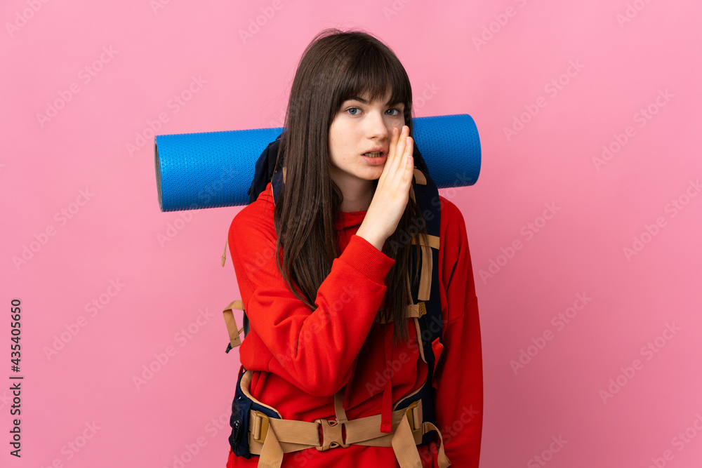 Mountaineer Ukrainian girl with a big backpack isolated on pink background whispering something Mountaineer Ukrainian girl with a big backpack isolated on pink background whispering something