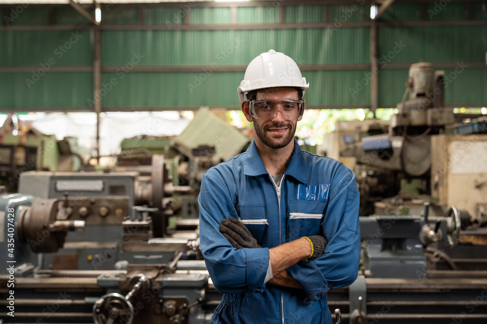Portrait of male factory worker working and standing in front of manufacturing machinery in the industry factory Portrait of male factory worker working and standing in front of manufacturing machinery in the industry factory