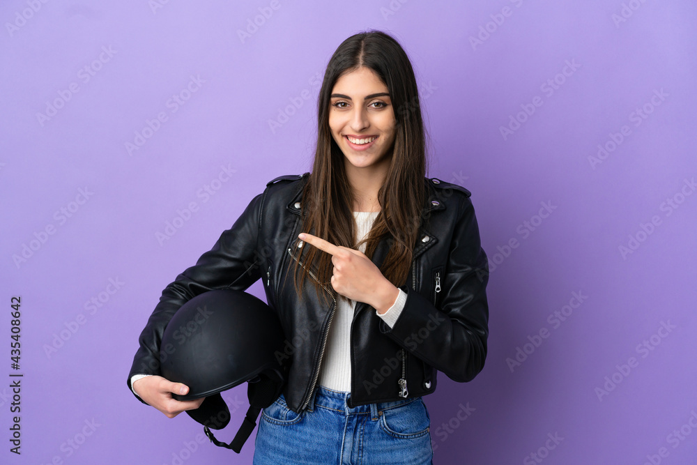 Young caucasian woman with a motorcycle helmet isolated on purple background pointing to the side to present a product Young caucasian woman with a motorcycle helmet isolated on purple background pointing to the side to present a product