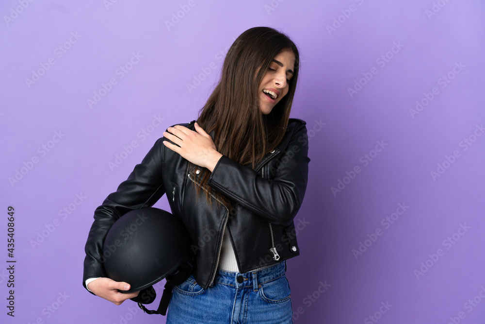 Young caucasian woman with a motorcycle helmet isolated on purple background suffering from pain in shoulder for having made an effort Young caucasian woman with a motorcycle helmet isolated on purple background suffering from pain in shoulder for having made an effort