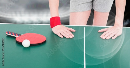 Composition of mid section of female table tennis player leaning on table with ball and racket