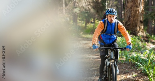 Fototapeta Naklejka Na Ścianę i Meble -  Composition of fit caucasian man riding bicycle in forest with blur