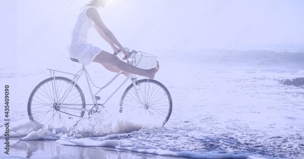 Fototapeta premium Composition of woman riding bike on beach with copy space