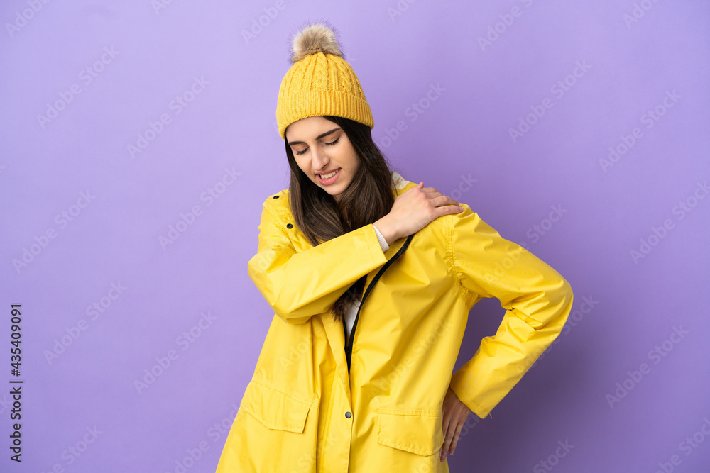 Young caucasian woman wearing a rainproof coat isolated on purple background suffering from pain in shoulder for having made an effort