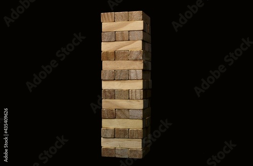 A game of Jenga on a black background. Wooden figurines
