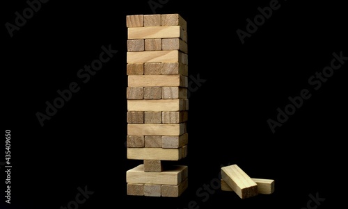 Jenga game. On a black background. There are no two elements at the bottom. Unstable Jenga