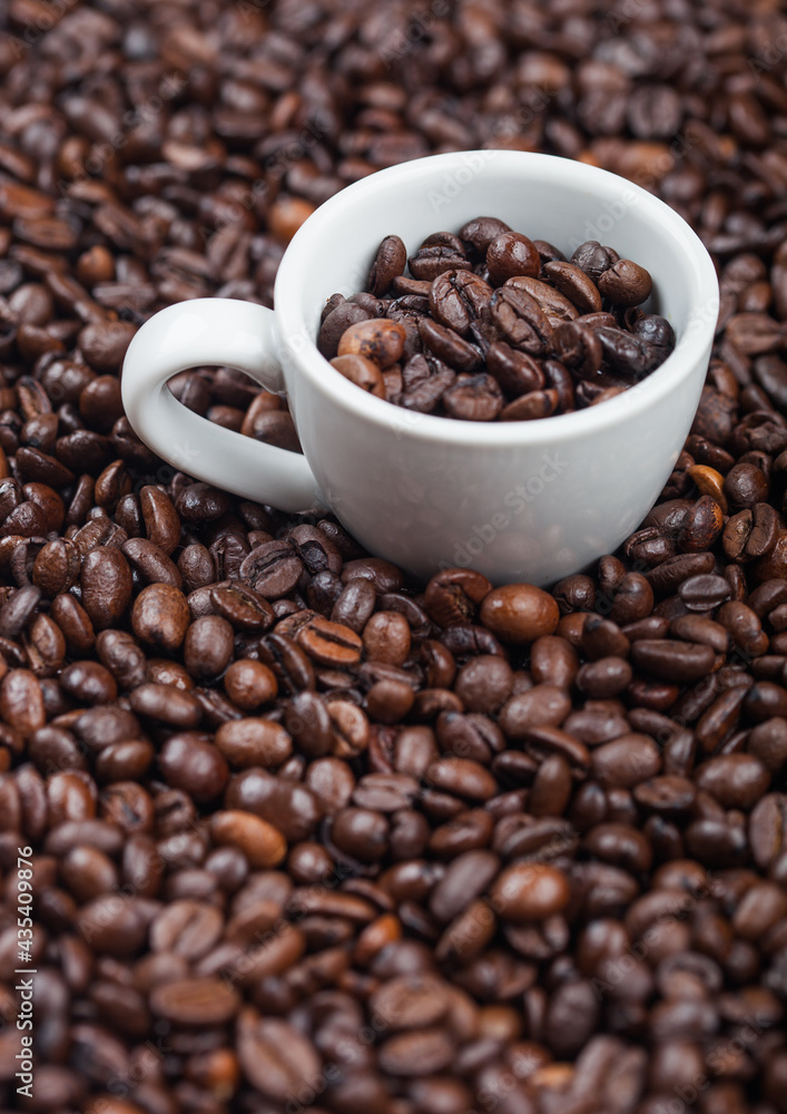 White espresso cup with fresh raw coffee beans inside beans background. White espresso cup with fresh raw coffee beans inside beans background.