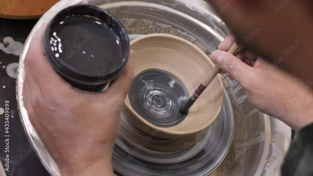 Pottery painting on clay pot. Handmade workshop ceramic. Earthenware. Painting ceramic pot with paint brush in pottery class potter workshop wheel. Potter work hands close up painting pottery making Pottery painting on clay pot. Handmade workshop ceramic. Earthenware. Painting ceramic pot with paint brush in pottery class potter workshop wheel. Potter work hands close up painting pottery making