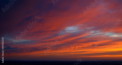 Beautiful orange bright sunset. The clouds are painted in the colors of the sunset. Bright colors of the sky. Bloody Sunset