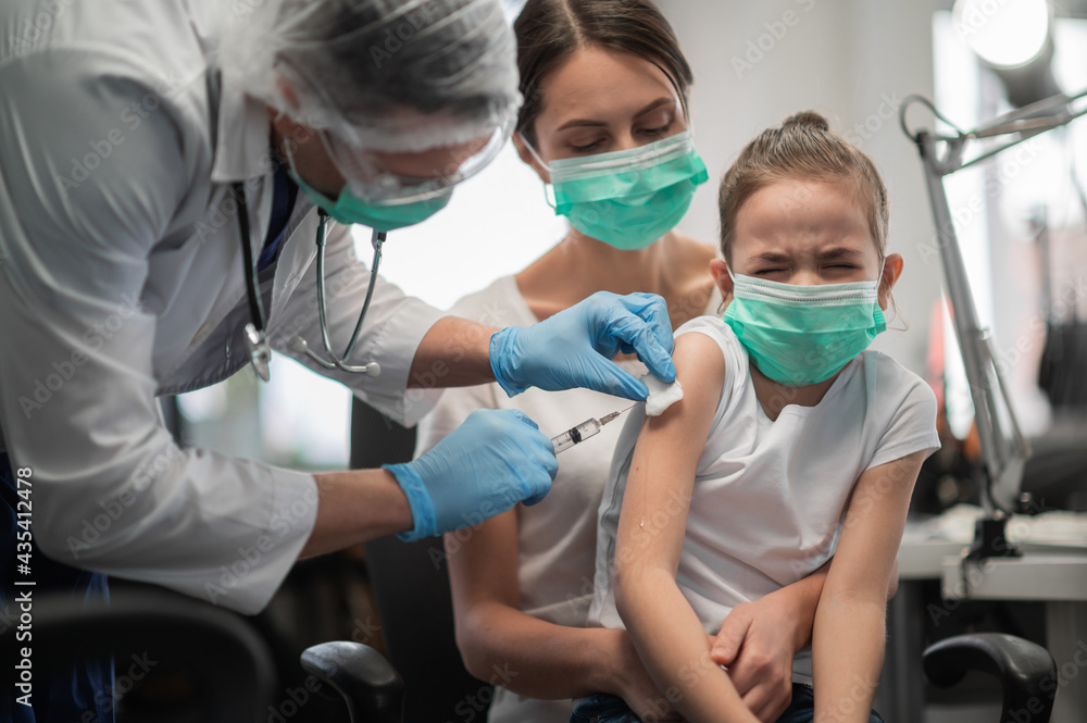A doctor gives a frightened girl an injection in the shoulder to prevent infectious diseases A doctor gives a frightened girl an injection in the shoulder to prevent infectious diseases