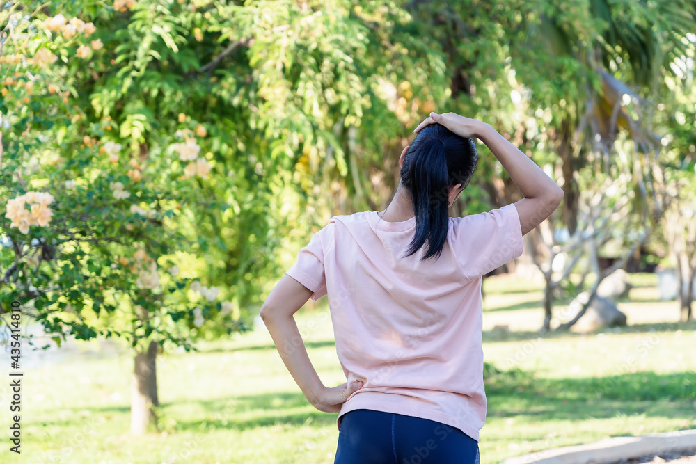 Back view of young fitness woman doing stretch exercise outdoors in park. Asian female stretching her arms above head for warming up before running or working out in morning. Healthy Concept. Back view of young fitness woman doing stretch exercise outdoors in park. Asian female stretching her arms above head for warming up before running or working out in morning. Healthy Concept.
