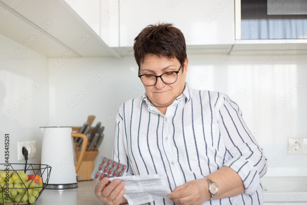 Senior woman reading instruction before taking medicines at home. Senior woman reading instruction before taking medicines at home.