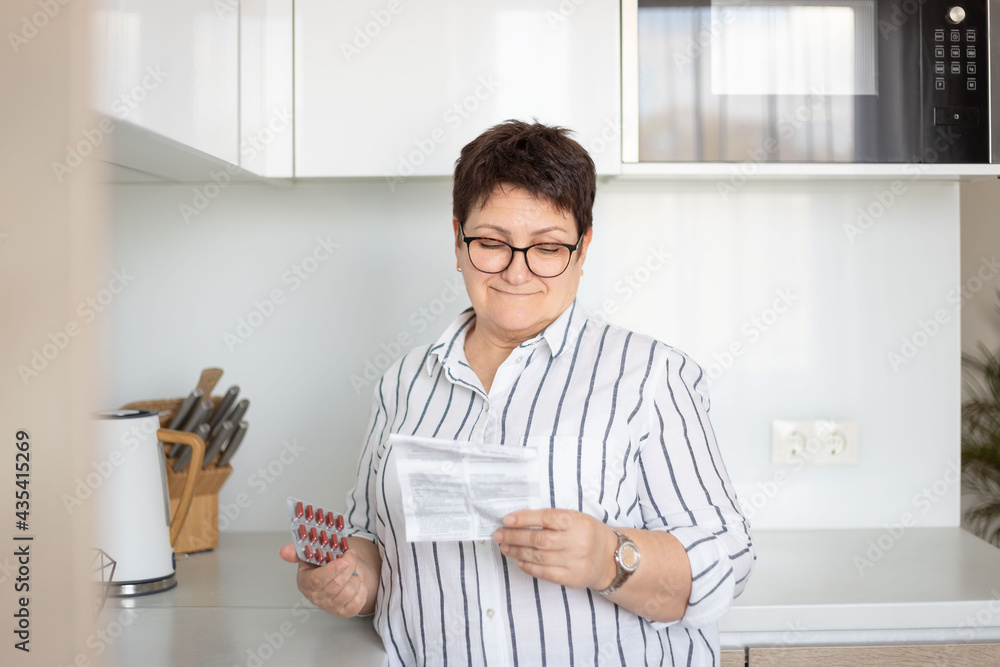 Senior woman reading instruction before taking medicines at home. Senior woman reading instruction before taking medicines at home.