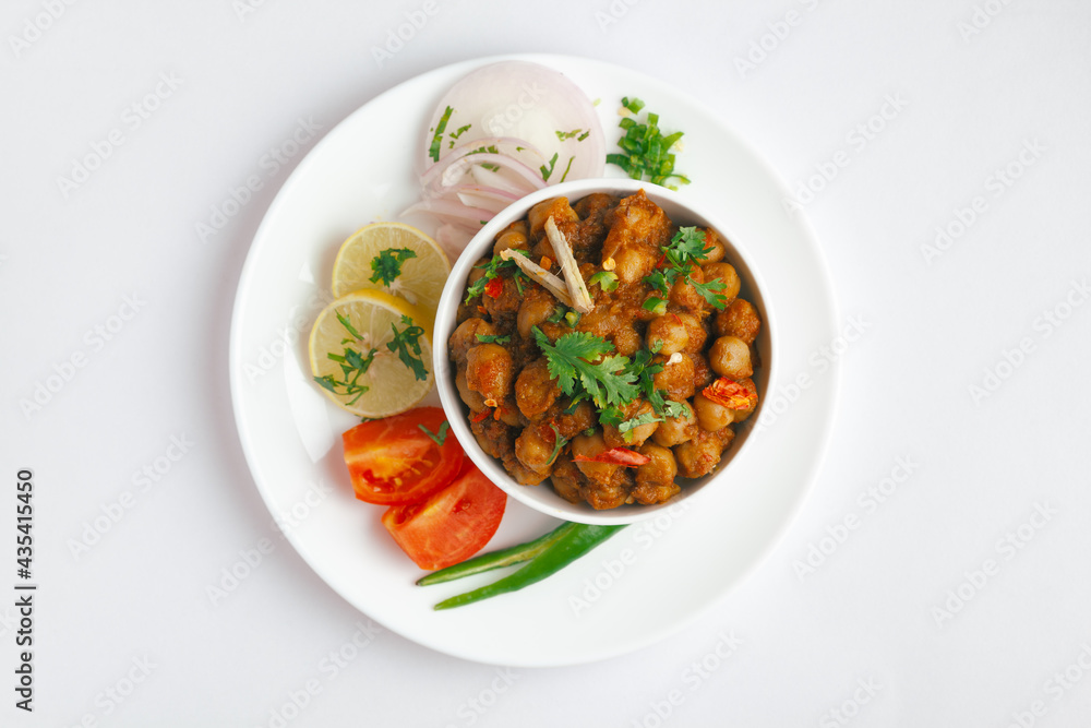 Chickpeas masala (Spicy chola or chhole curry) garnished with fresh green coriander and ingredients. Served in a ceramic bowl. An Classic Indian typical Panjabi street food. Chickpeas masala (Spicy chola or chhole curry) garnished with fresh green coriander and ingredients. Served in a ceramic bowl. An Classic Indian typical Panjabi street food.