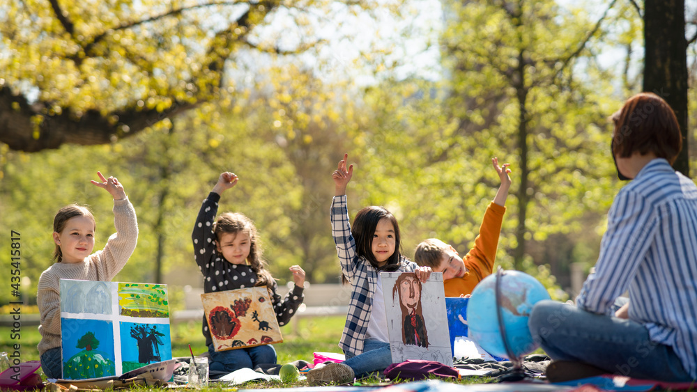 © Halfpoint - Small children with teacher outdoors in city park, learning group education and art concept.
