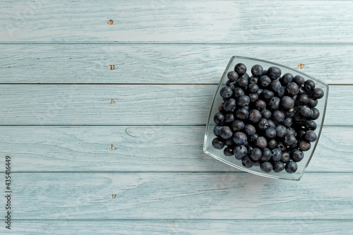 Blueberries in a glass bowl on wooden table top. Top view with copy space. Flat lay.