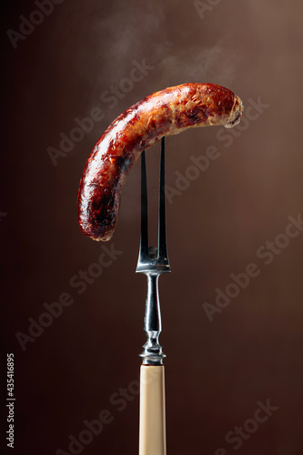Grilled Bavarian sausage on a fork.