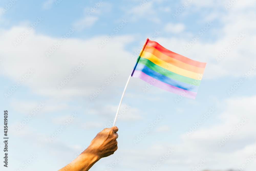 Unrecognizable person hand waving rainbow gay pride flag. activist for the rights of lgbt people. Unrecognizable person hand waving rainbow gay pride flag. activist for the rights of lgbt people.
