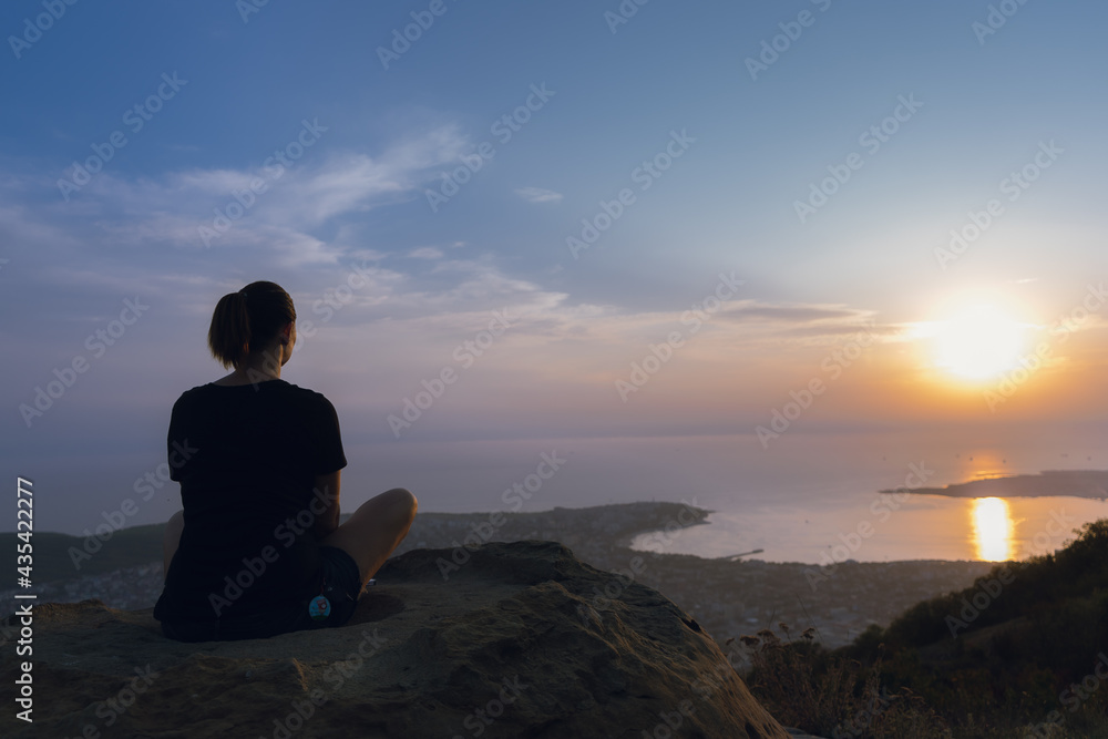 silhouette of a person sitting on a cliff