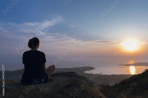 silhouette of a person sitting on a cliff