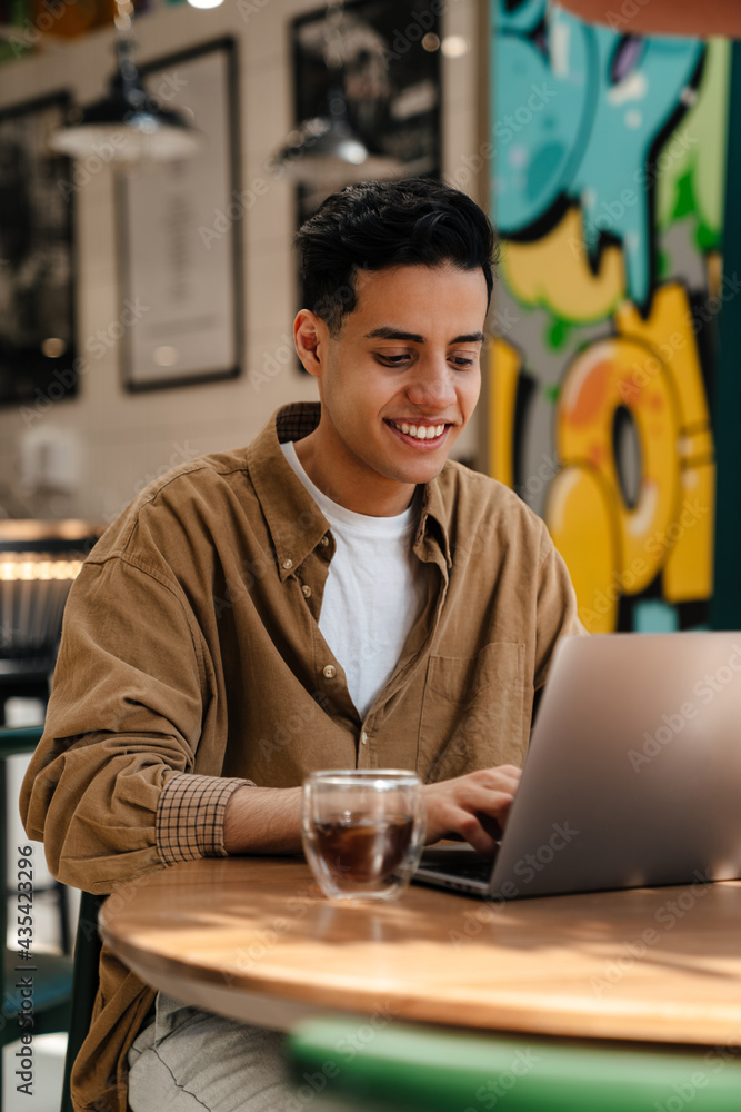 Young hispanic man student sitting at the cafe table indoors