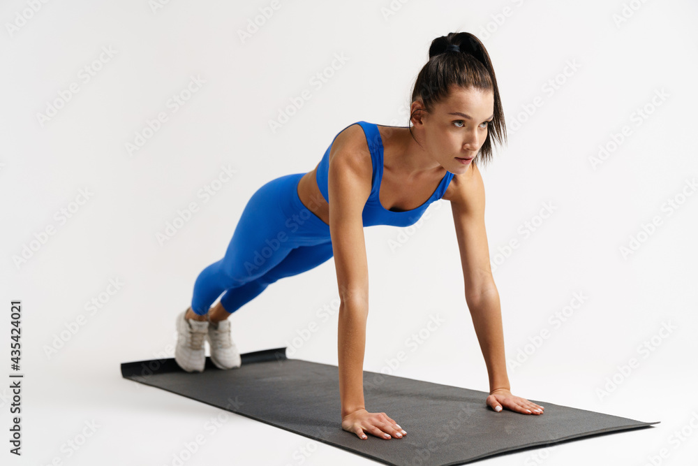 Slim young white sportswoman exercising on a fitness mat Slim young white sportswoman exercising on a fitness mat