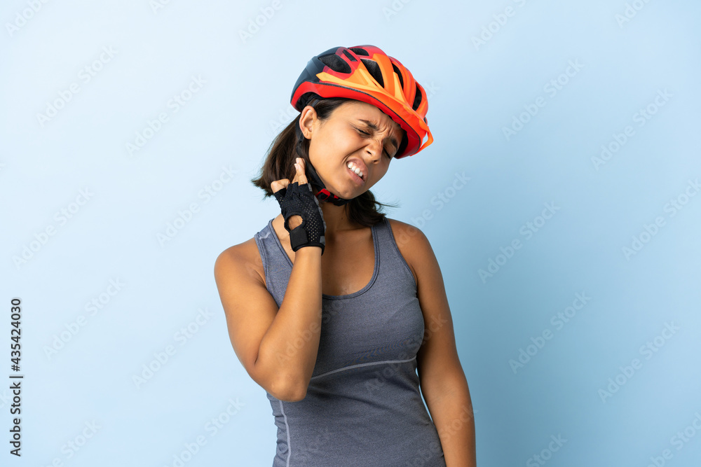 Young cyclist woman isolated on blue background with neckache - obrazy, fototapety, plakaty 