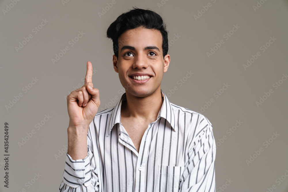 Brunette hispanic man in shirt smiling and pointing finger upward Brunette hispanic man in shirt smiling and pointing finger upward