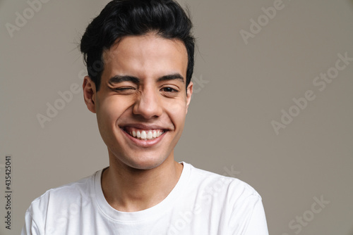 Brunette hispanic man in t-shirt smiling and winking at camera