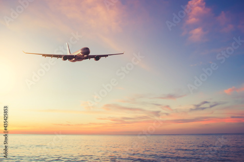 Airplane flying over tropical beach with smooth wave and sunset sky abstract background. © tonktiti